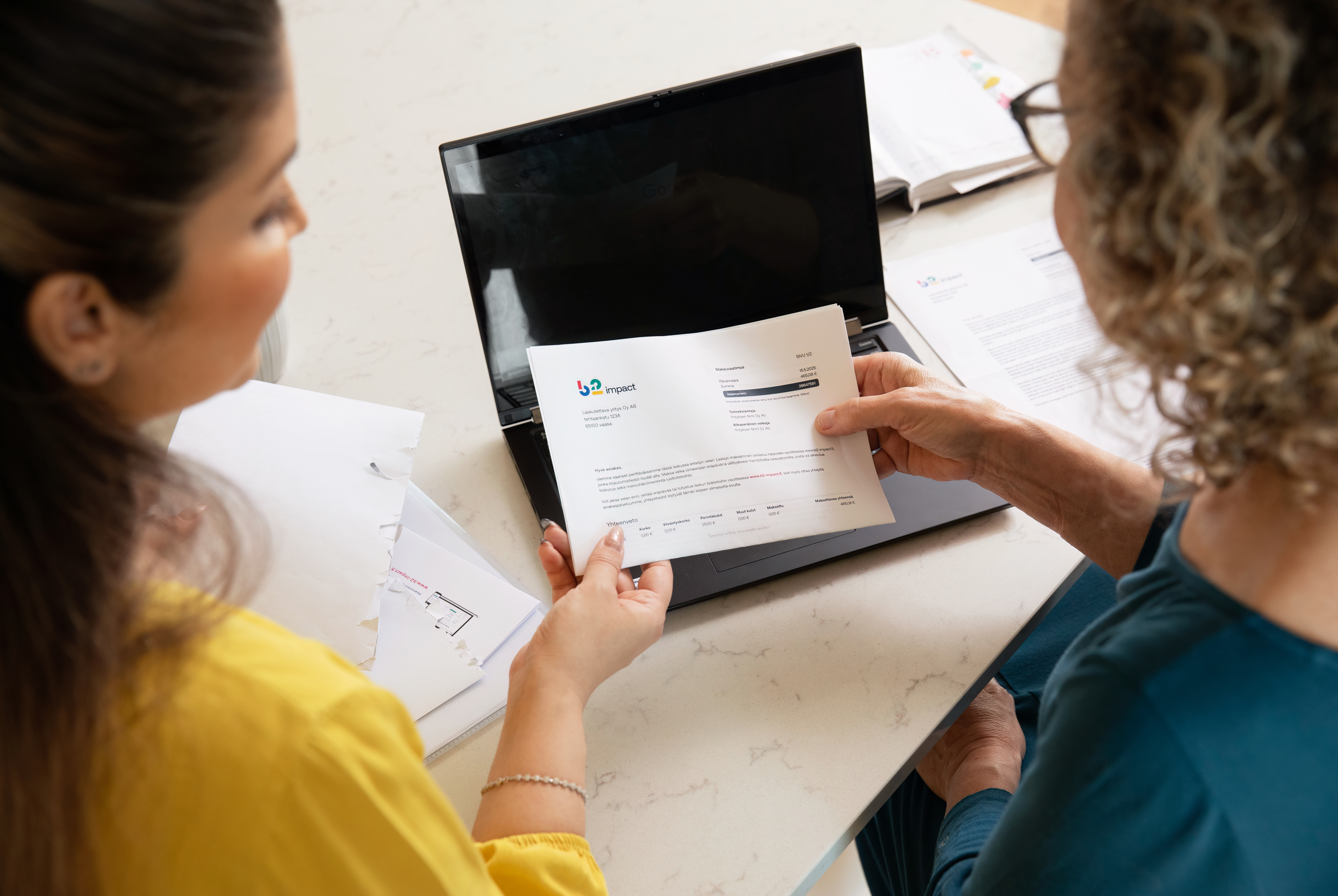 Kaksi naista tutkii laskua. 