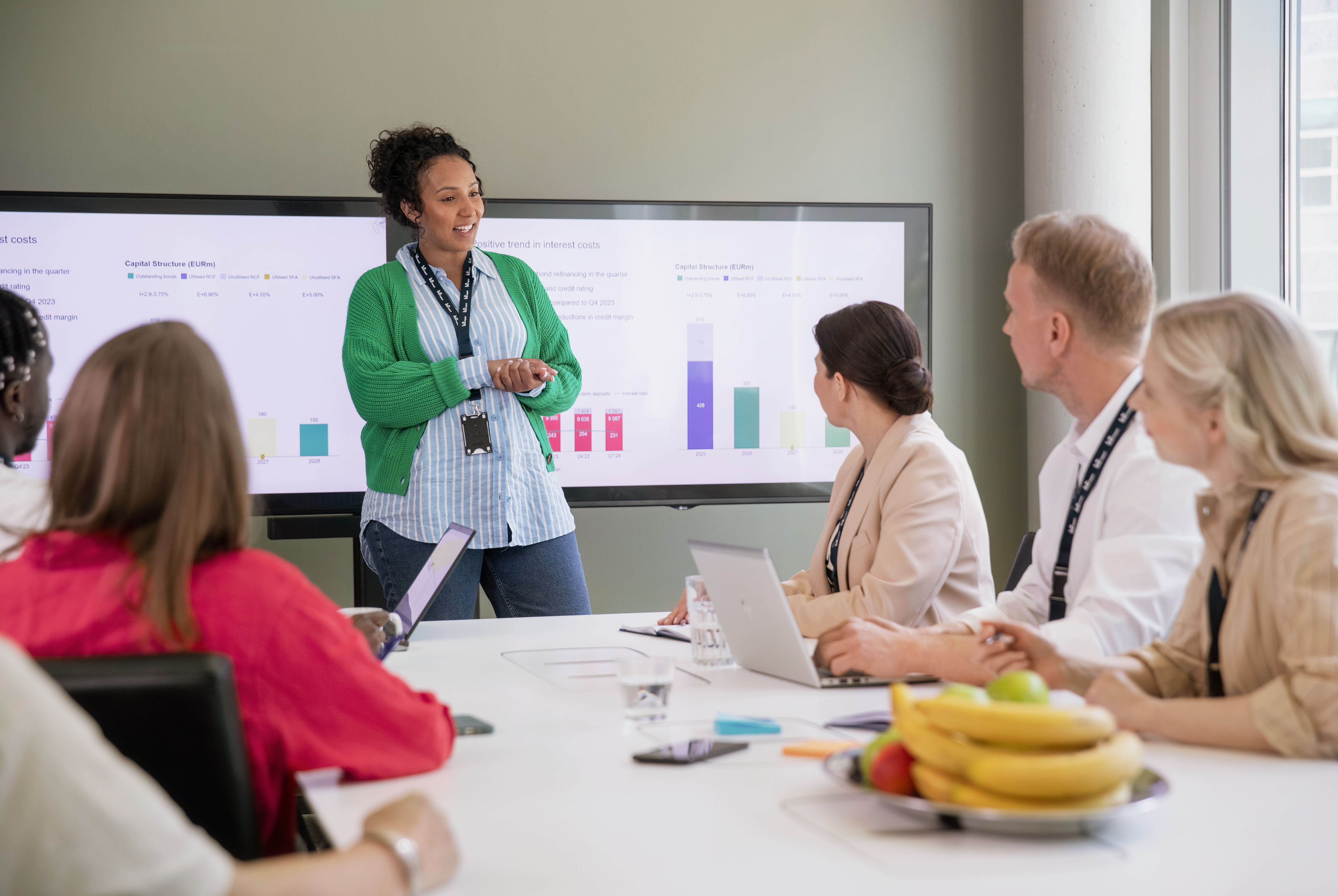A woman presents to the team in the meeting room.