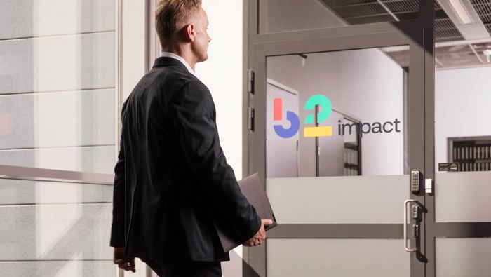 Mies kävelee kohti ovea, jossa lukee B2 Impact.